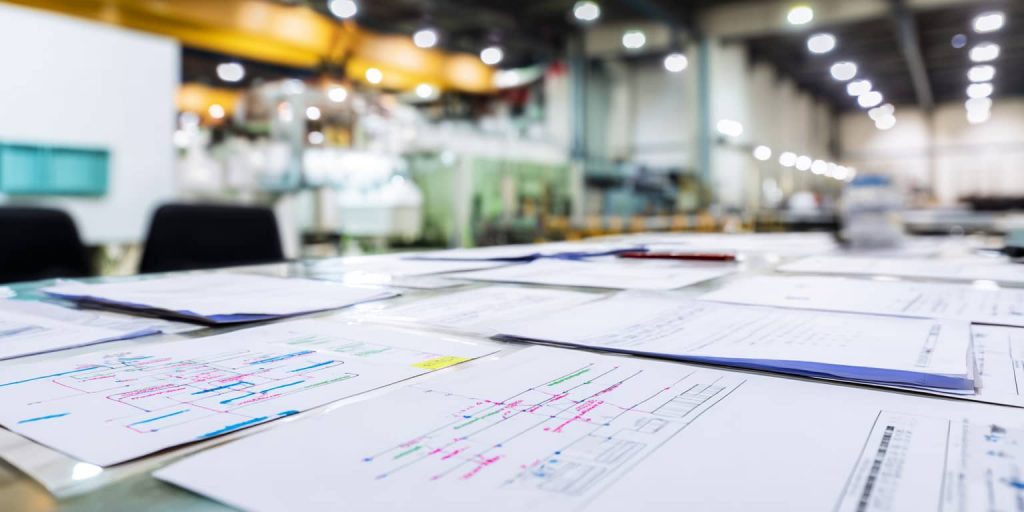 Projektmanagement-Dokumente und Prozesspläne in einer Industriehalle eines Automobilzulieferers